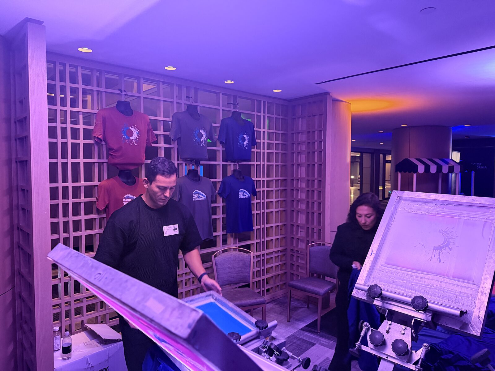 Wall of finished custom printed wedding keepsake shirts on display
